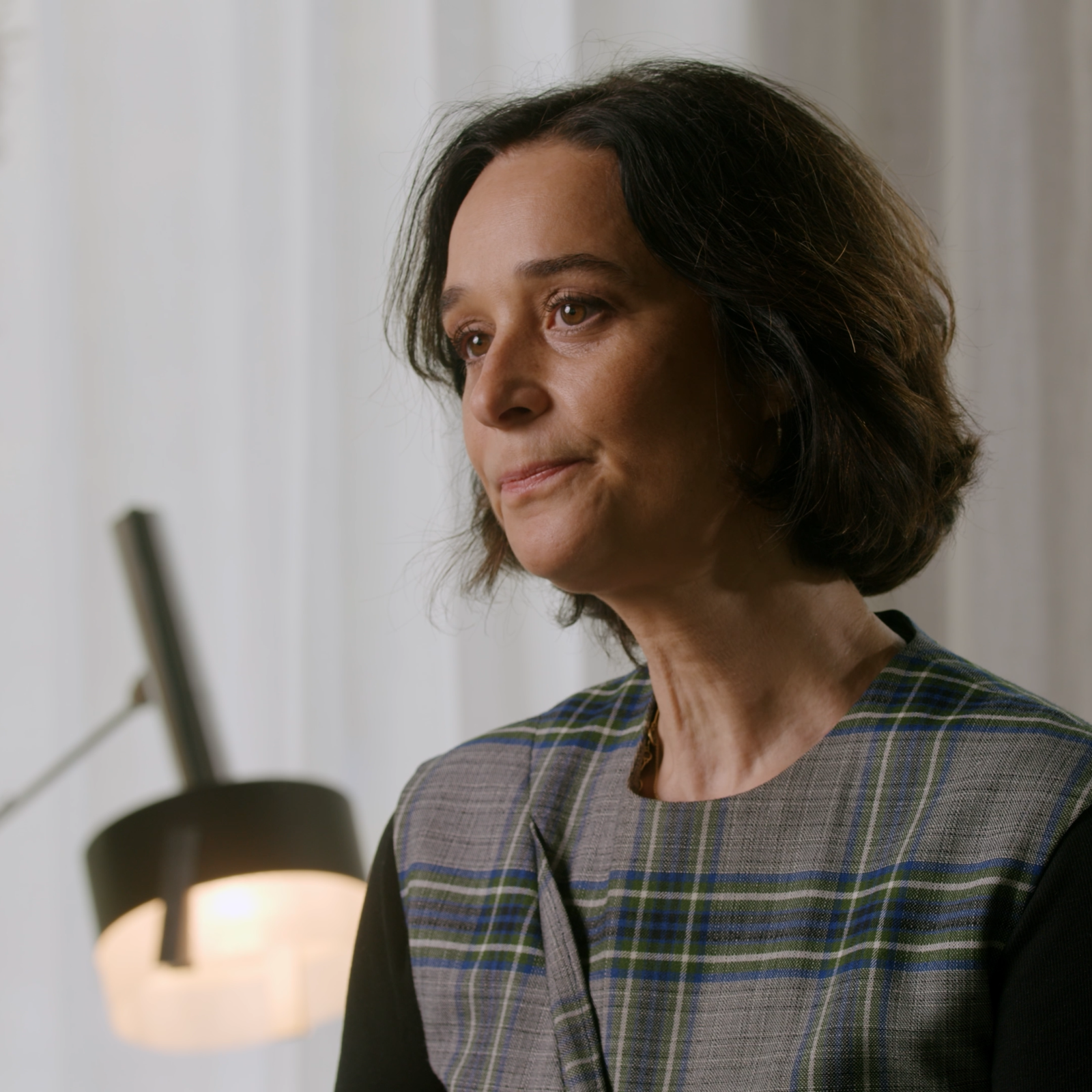 Portrait of Delphine Heenen speaking during a testimonial interview, with a soft neutral background.