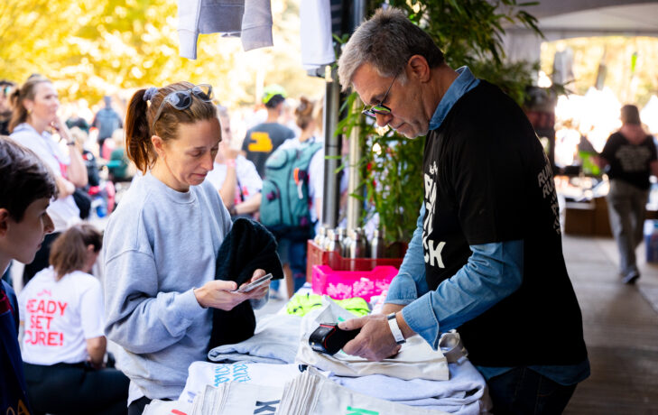 Volunteer helping at the Run to Kick merchandise stand during the KickCancer event.