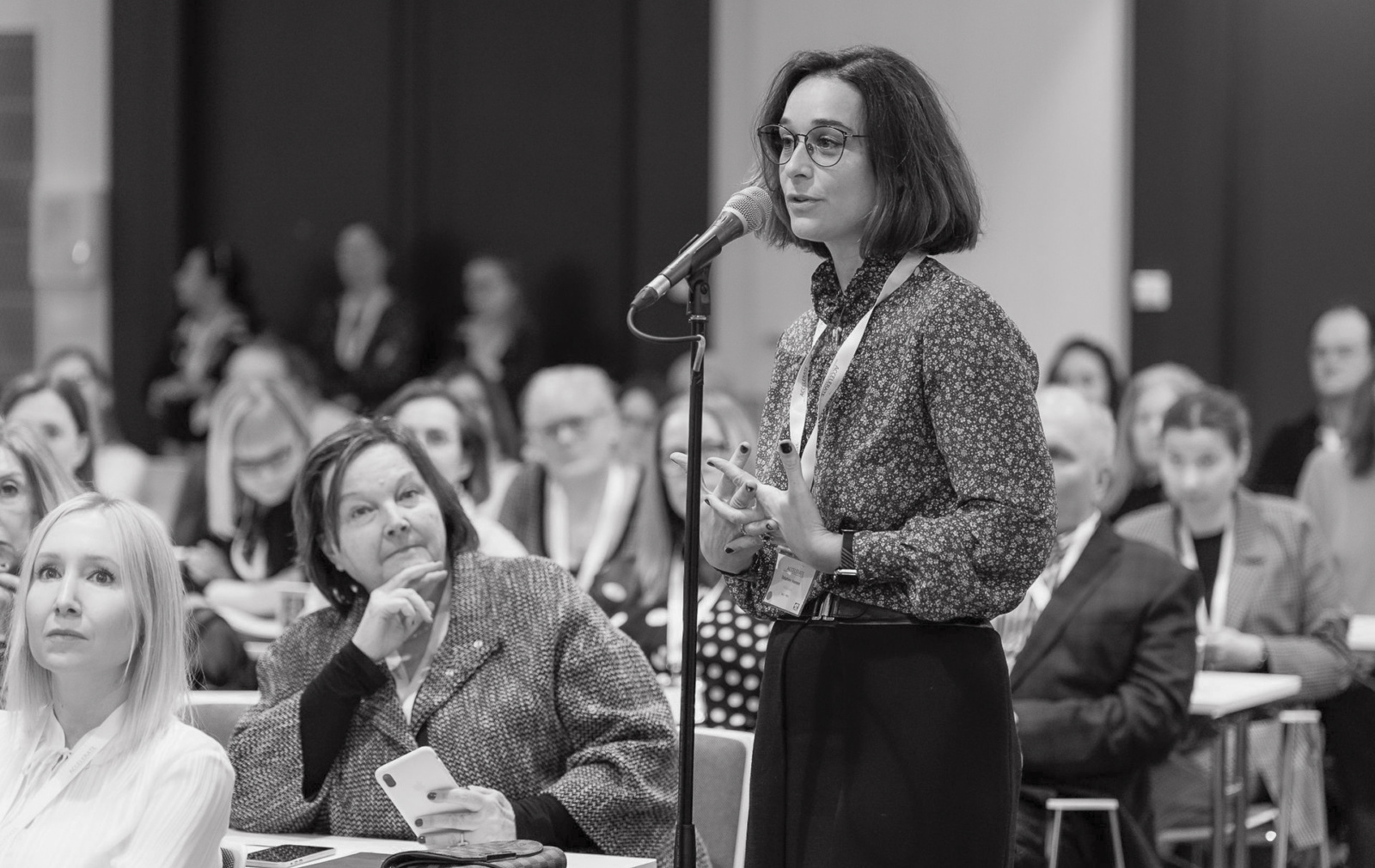 Delphine Heenen speaking at the ACCELERATE meeting, standing at a microphone in a conference room filled with participants.